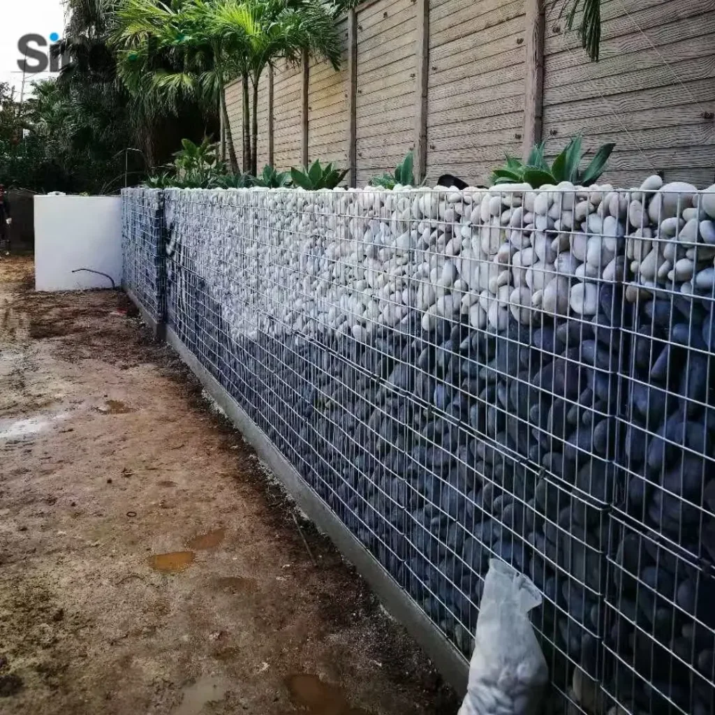 Gabion Retaining Walls by Retaining Walls Tauranga, featuring decorative white and black stones in mesh cages for stylish and durable garden support.