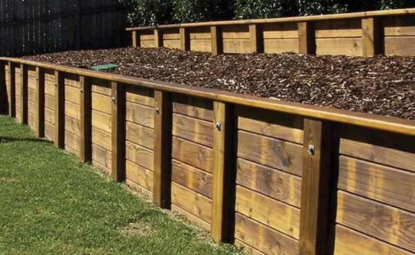 Timber Retaining Walls installed by Retaining Walls Tauranga, supporting a raised mulch-filled garden area in a residential yard.